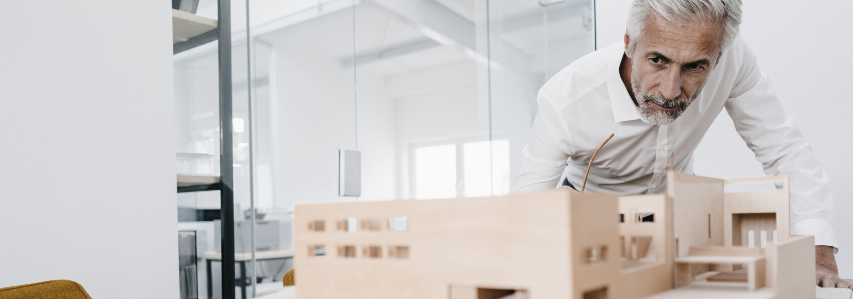 Mature Businessman Examining Architectural Model In Office