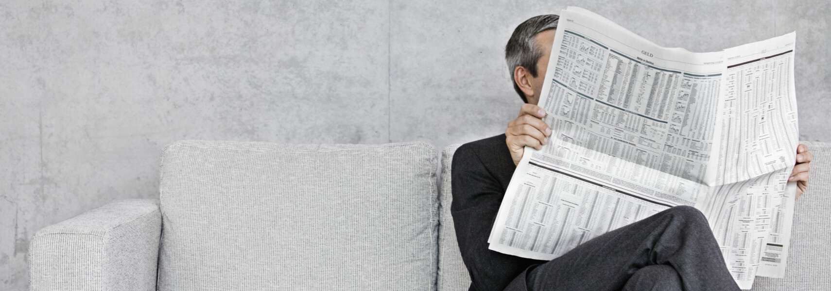 Man Reading Newspaper On Sofa