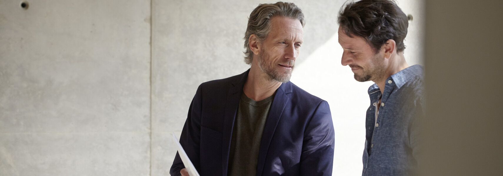 Two Men On Construction Site Discussing Document